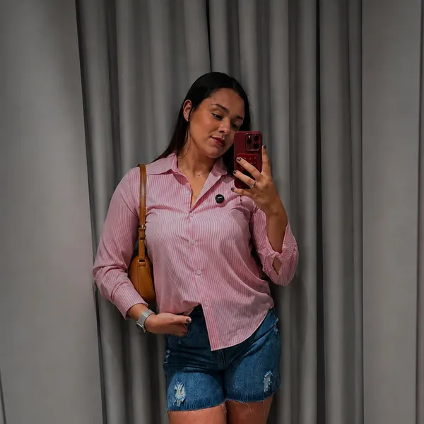 Cliente no provador da Loja Mariana com camisa rosa listrada e short jeans