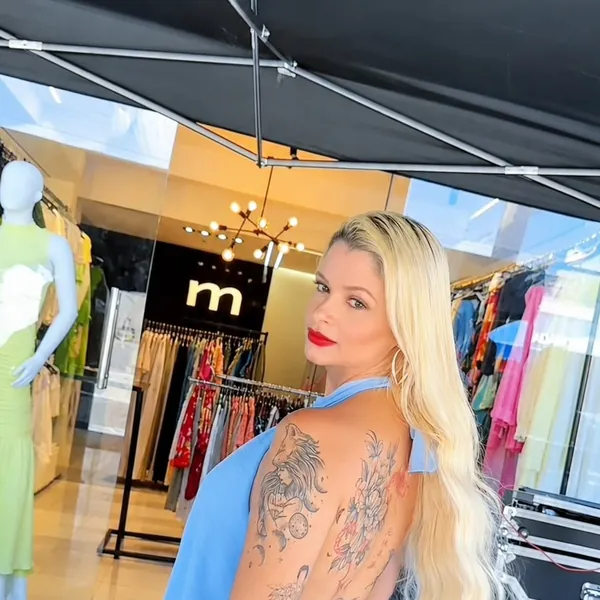 Cliente com vestido azul de costas nuas em frente à Loja Mariana